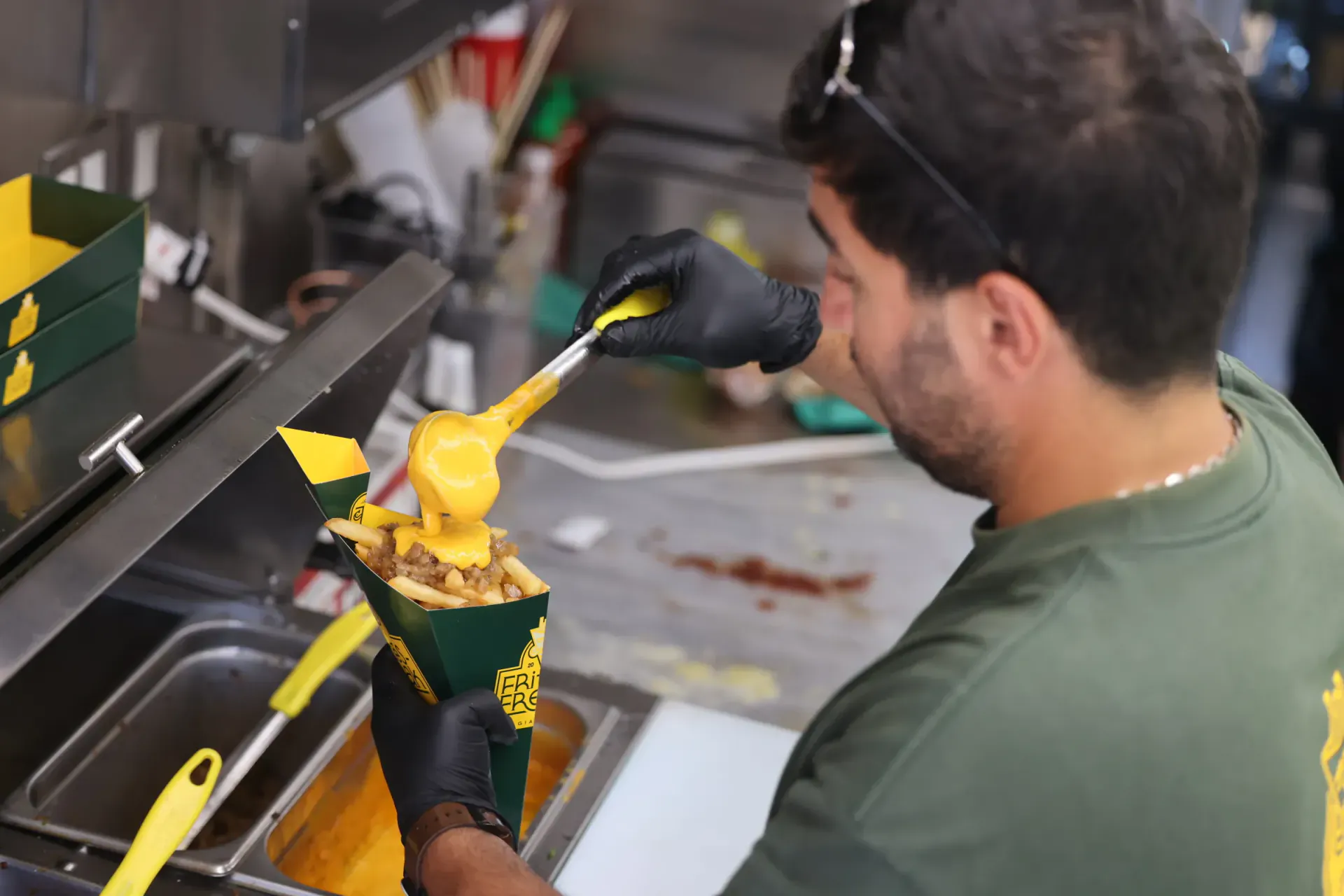 Warm cheese sauce pouring off the ladle onto a cone