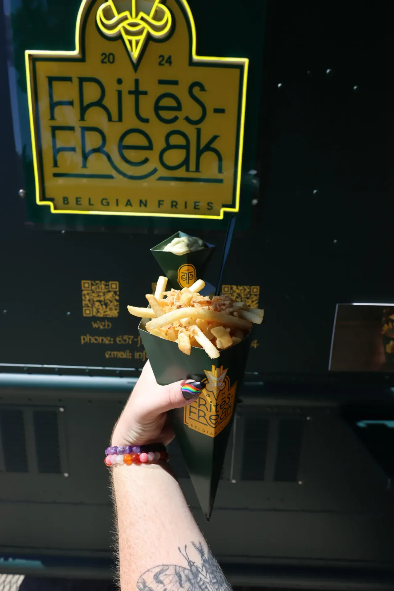 A loaded cone held up against the truck's lit FRitēS-FReaK sign